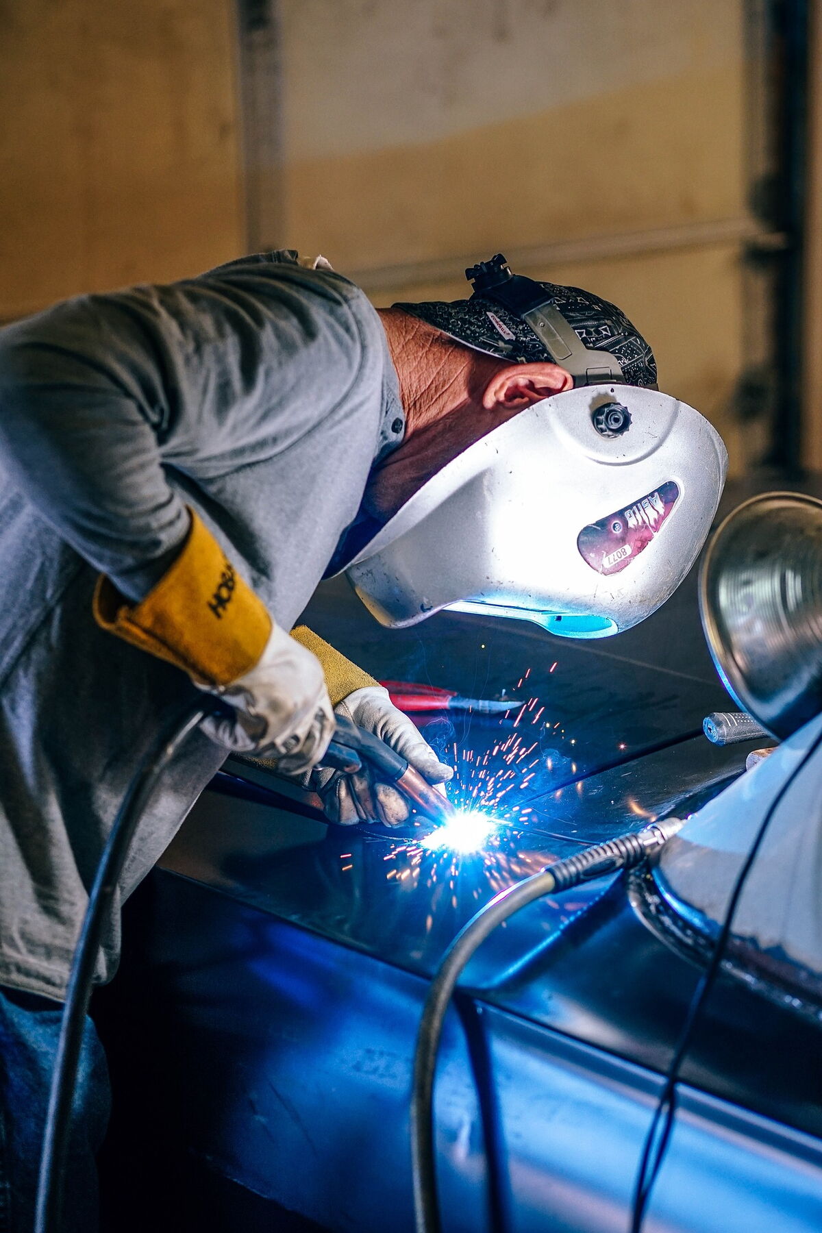 Schweißer mit Schutzhelm beim Schweißen, blaues Licht des Lichtbogens