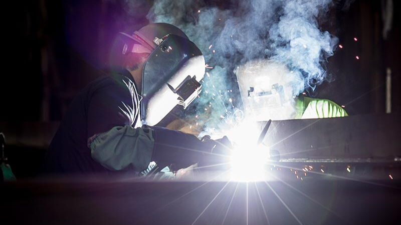 Schweißer mit Schutzhelm bei der Arbeit, helle Funken