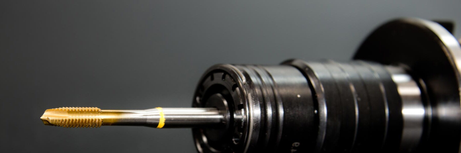 Gewindebohrer in einer Werkzeugaufnahme vor dunklem Hintergrund